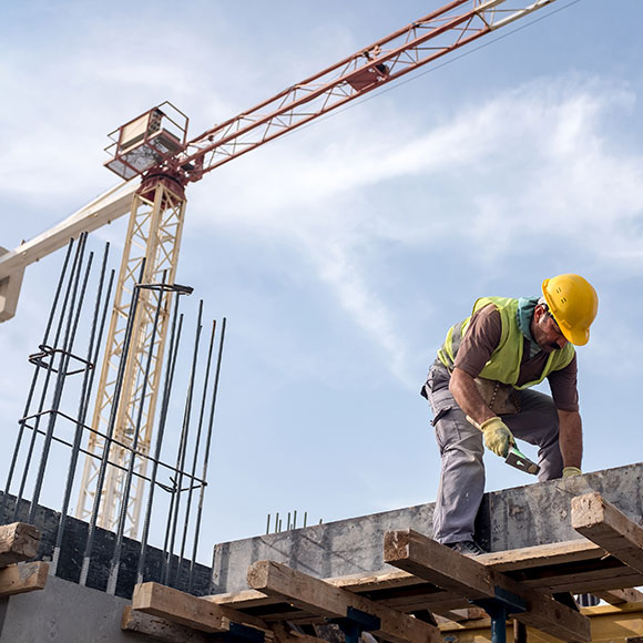 A construction worker on site with a crane in the background, all insured under a liability insurance with Insure 313.