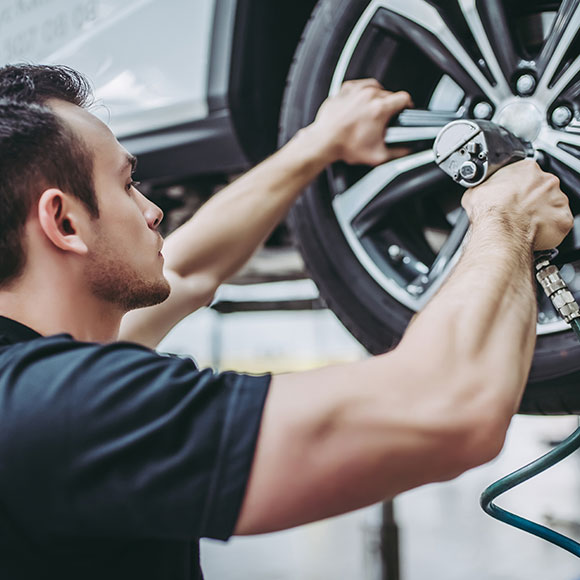 A mechanic fitting a tyre with a tool insured by a motor trade insurance policy with Insure 313 insurance brokers.